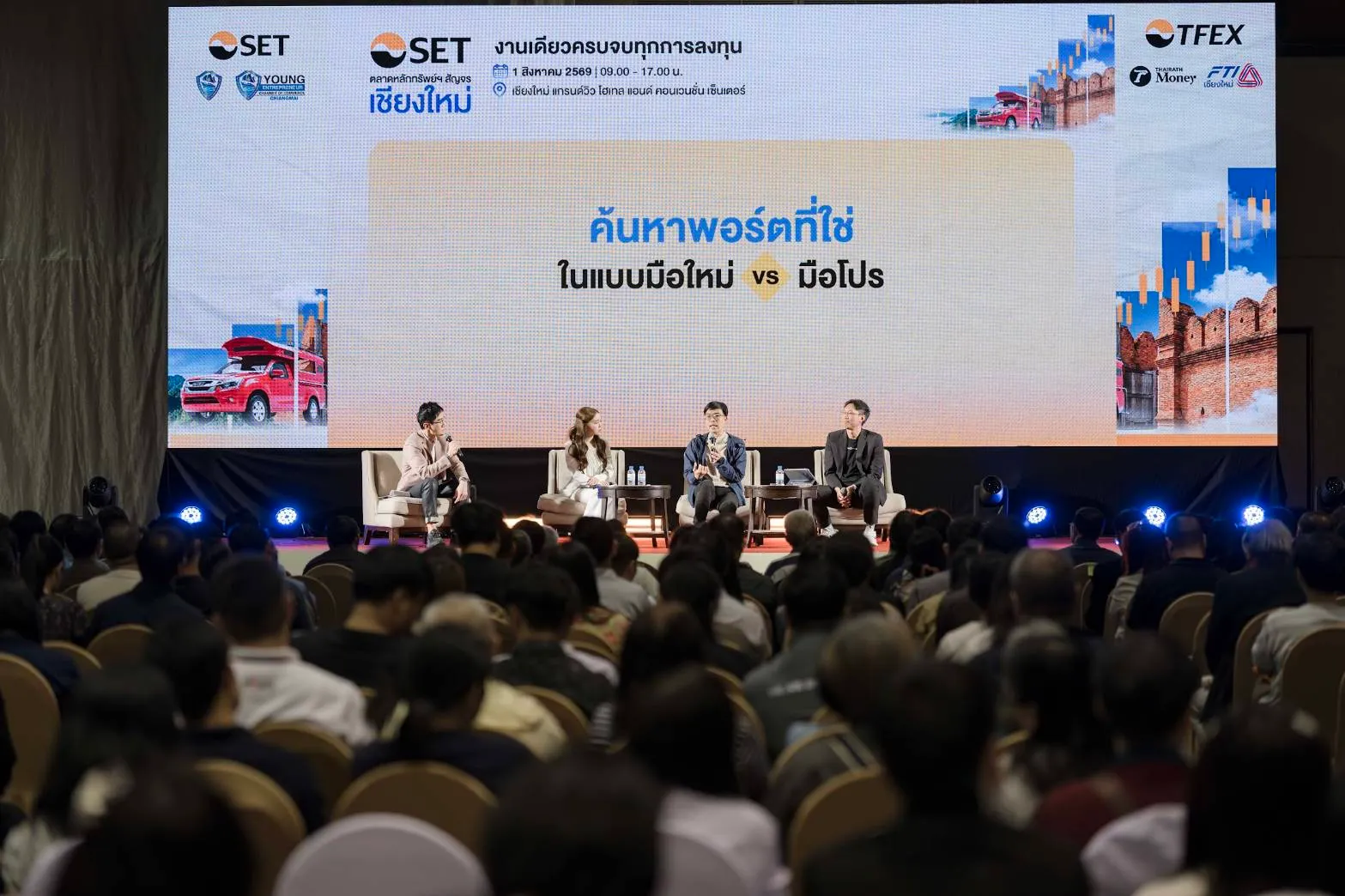 ผู้ร่วมเสวนา 4 ท่านนั่งบนเวทีพูดคุยหัวข้อ "ค้นหาพอร์ตที่ใช่ ในแบบมือใหม่ vs มือโปร" ในงานตลาดหลักทรัพย์ฯ สัญจรเชียงใหม่ ท่ามกลางผู้เข้าร่วมงานจำนวนมากที่นั่งฟังอย่างตั้งใจ