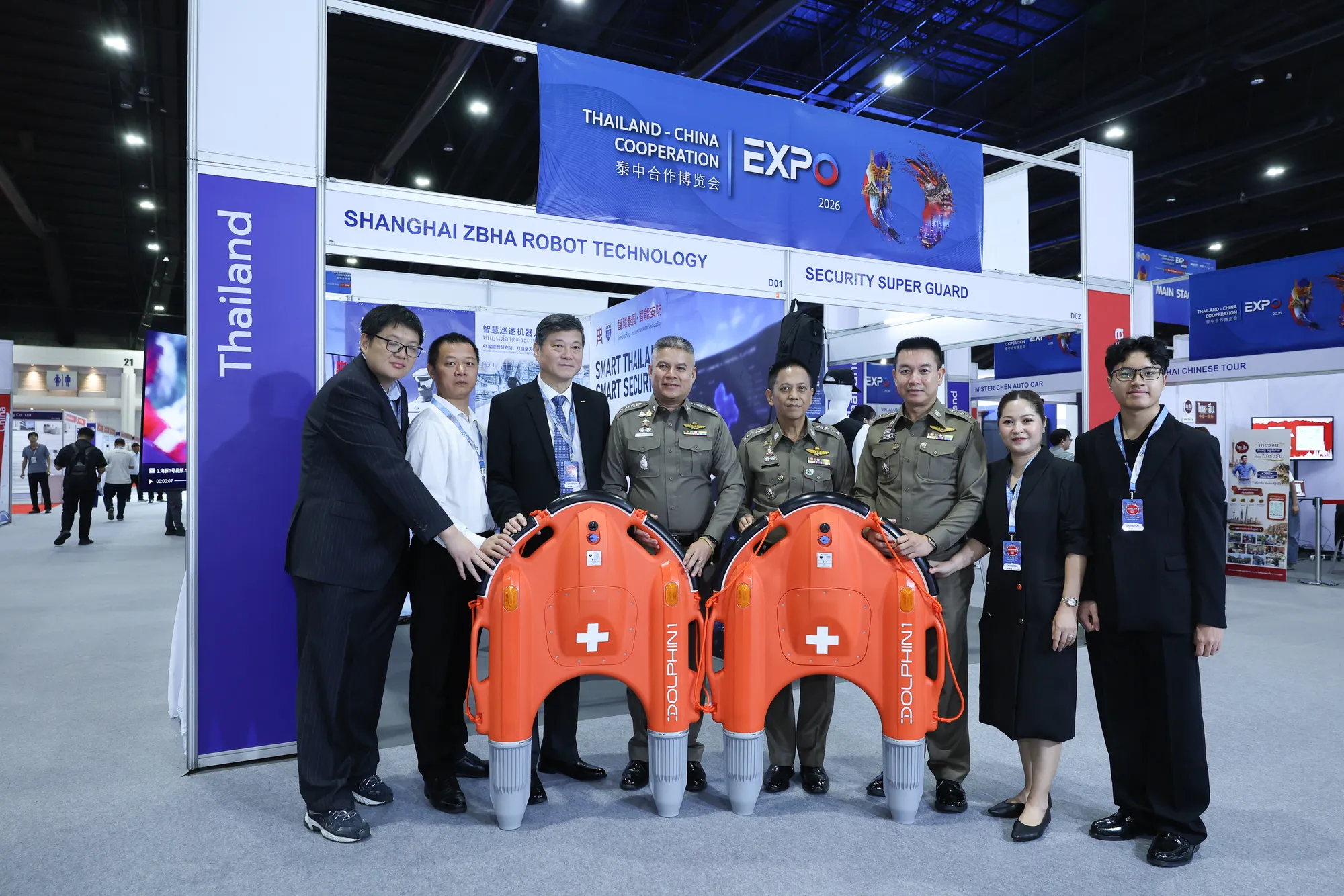 คณะเจ้าหน้าที่และตัวแทนบริษัท Shanghai ZBHA Robot Technology ถ่ายภาพร่วมกันกับหุ่นยนต์กู้ภัยทางน้ำ Dolphin สีส้มสองเครื่องในงาน Thailand-China Cooperation Expo 2026
