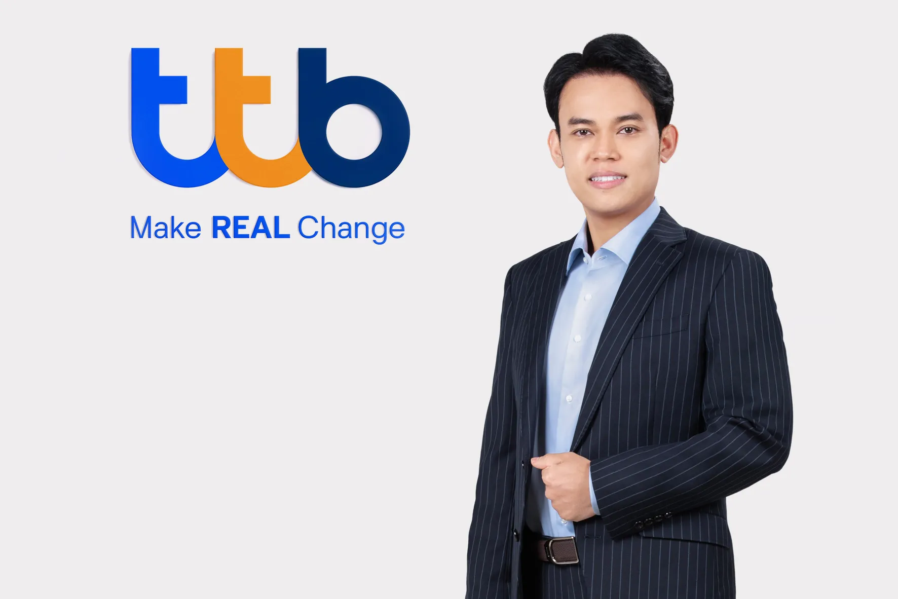 ชายสวมสูทลายทางสีกรมท่ายืนยิ้มข้างโลโก้ทีทีบีและข้อความ "Make REAL Change" สื่อถึงข่าวทีทีบียกระดับการเงินเพื่อความยั่งยืนสนับสนุนธุรกิจไทยรับมือมาตรการสิ่งแวดล้อม