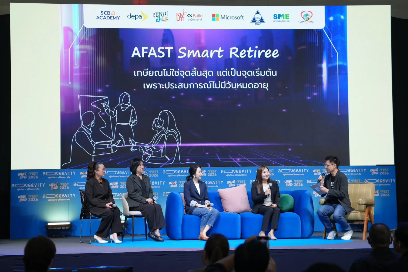 เวทีเสวนา "AFAST Smart Retiree" ในงานมนุษย์ต่างวัย Fest 2026 มีวิทยากร 4 ท่านนั่งบนโซฟาสีฟ้าและผู้ดำเนินรายการถือไมโครโฟนสัมภาษณ์ พร้อมโลโก้หน่วยงานพันธมิตรอย่าง SCB Academy, depa, KMUTT และ Microsoft ปรากฏอยู่บนจอด้านหลัง