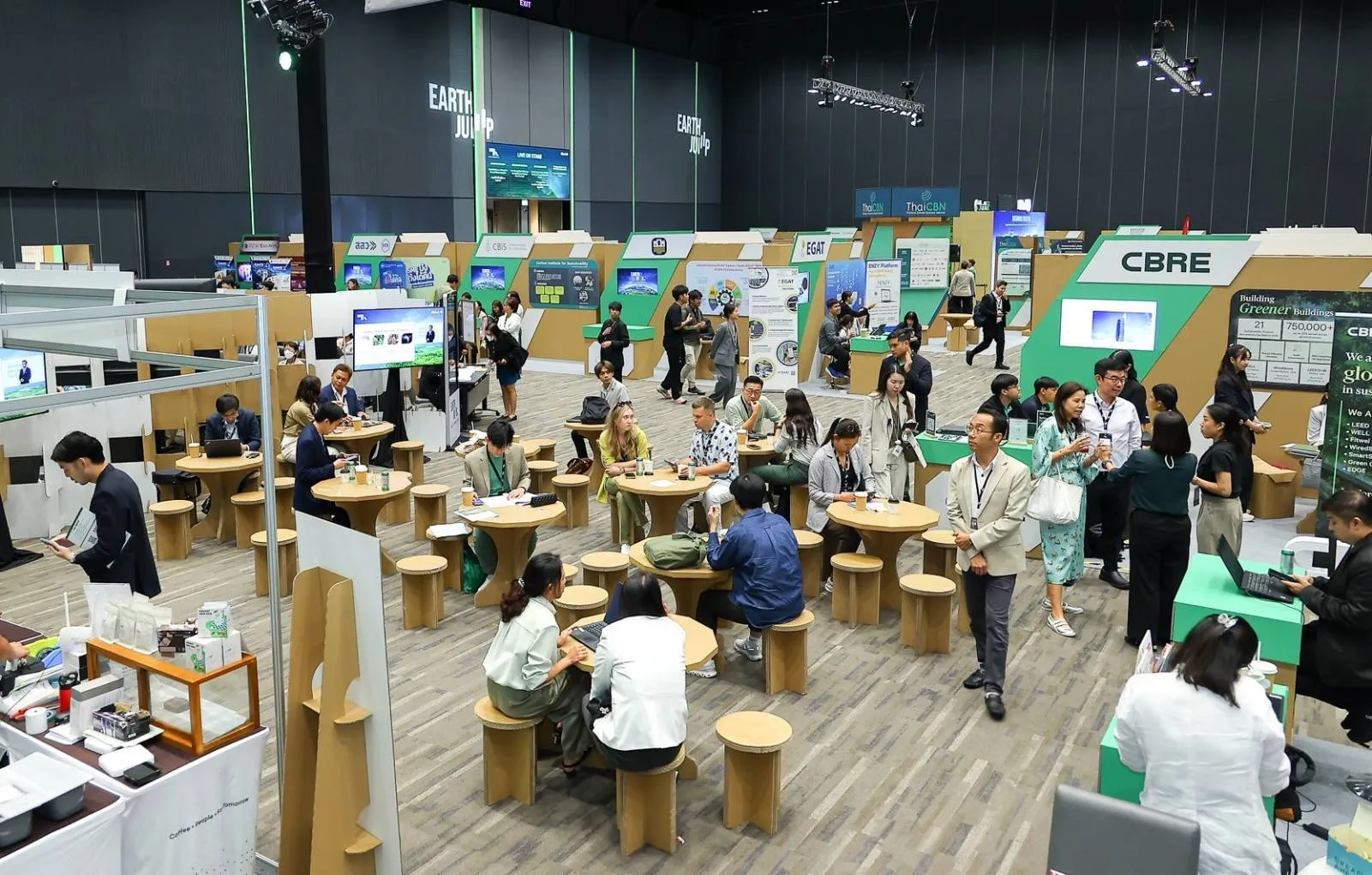 ภาพมุมสูงงาน EARTH JUMP แสดงบูธนิทรรศการต่างๆ ที่ทำจากกระดาษรีไซเคิล พร้อมโต๊ะเก้าอี้กระดาษให้ผู้เข้าร่วมงานนั่งพูดคุยกันภายในฮอลล์จัดงาน