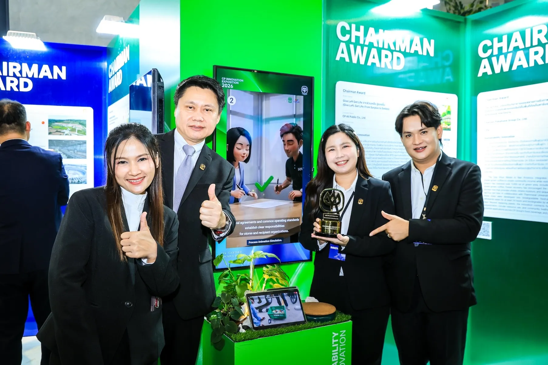 ทีมผู้บริหารและพนักงานซีพี ออลล์ 4 คนถ่ายภาพร่วมกันพร้อมถ้วยรางวัล Chairman Award หน้าบูธนิทรรศการสีเขียวในงาน CP Innovation Exposition 2026