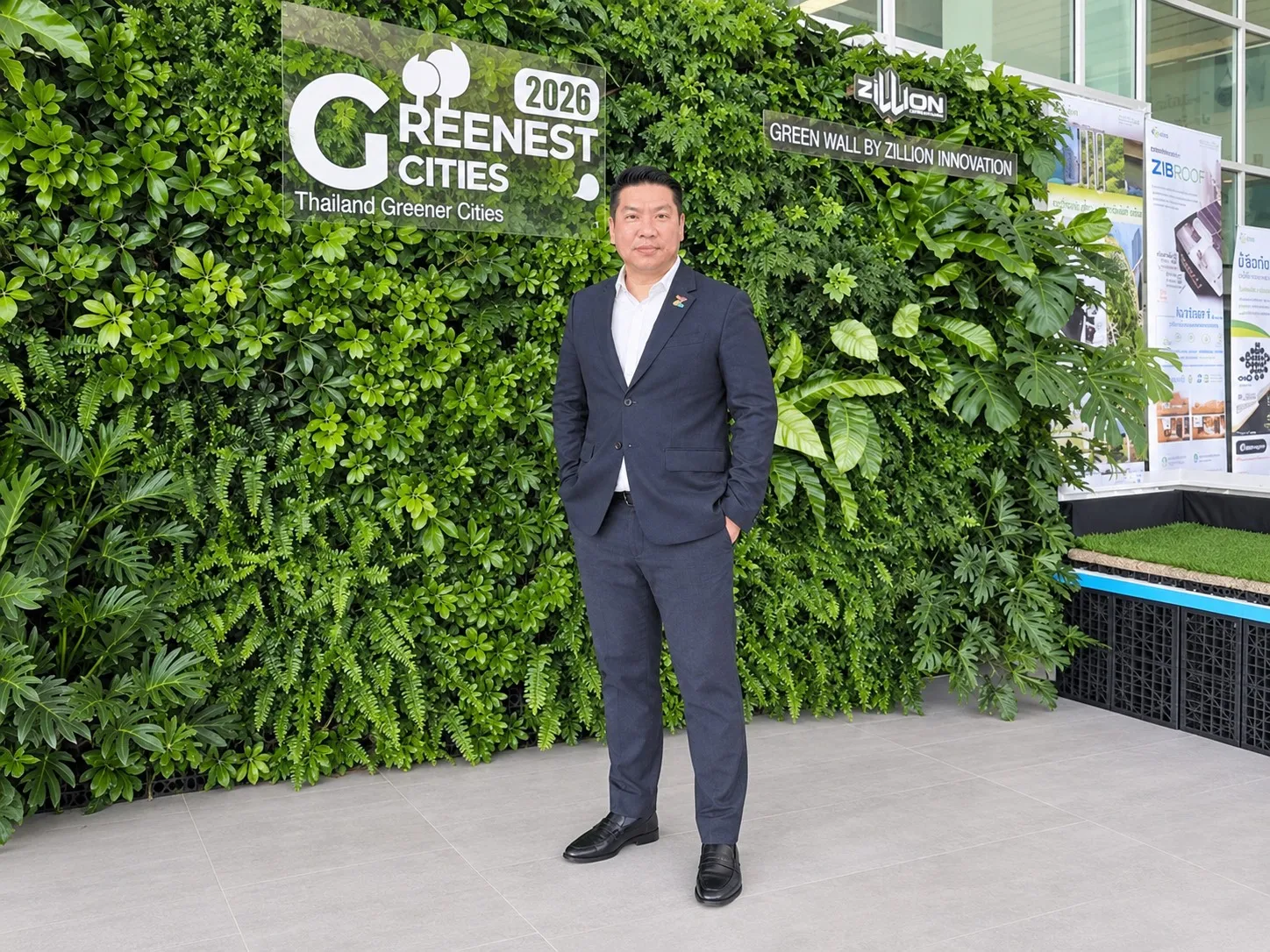 ผู้บริหารสวมสูทสีกรมท่ายืนถ่ายภาพหน้ากำแพงต้นไม้สีเขียว พร้อมป้าย Greenest Cities 2026 และป้าย Green Wall by Zillion Innovation ในงานลงนาม MOU ผลักดันภาคใต้สู่เมืองเขียวปี 2040
